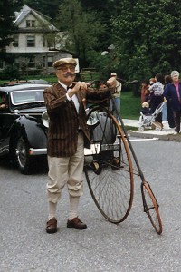 Hank with an antique bicycle in a parade from an earlier era.